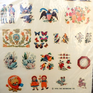 May include: A sheet of vintage iron-on transfer stickers featuring a variety of designs, including birds, butterflies, flowers, a clock, a swan, an eagle, and a lion. The stickers are printed on a white background with colorful details.