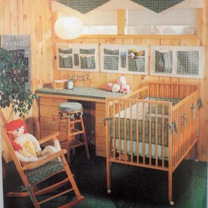 May include: A nursery scene with a wooden crib, changing table, and rocking chair. The crib and chair have green plaid accents. A doll sits in the rocking chair. The room has a wooden wall and a sign with the alphabet.