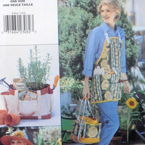 Puede incluir: Un delantal de jardinería y un bolso tote con un estampado de girasoles. El delantal tiene bolsillos y un ribete amarillo. El bolso tote tiene un diseño de girasol a juego. La imagen también muestra una bolsa de herramientas de jardinería con una planta y herramientas de jardinería.