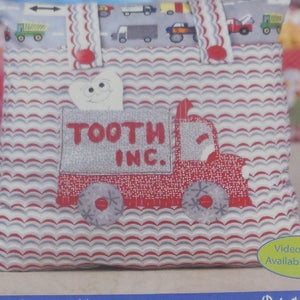 May include: A tooth fairy pillow featuring a red truck design with the text "TOOTH INC." on the front. The pillow has a wavy pattern in red, white, and grey. A smiling tooth is in a pocket.
