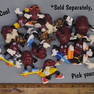May include: A collection of 1980s cool grape character figurines. The figurines are all different colors and have different accessories, such as a skateboard, a guitar, and a trumpet. The text "*Sold Separately, man!" and "Pick your fave!" is visible in the image.