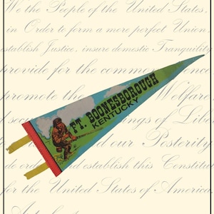 May include: A vintage pennant with a triangular shape, displaying the text "FT. BOONESBOROUGH KENTUCKY" in black on a blue background. It features an illustration of a person with a rifle. The pennant has a red border and yellow tabs.