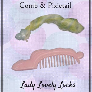 May include: A pink plastic comb and a green and white yarn pixie tail for a doll. The comb has the words "Lady Lovely Locks" printed on it.