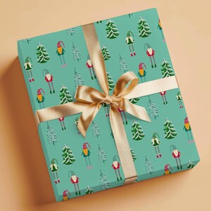 May include: A wrapped gift box with a teal background and a repeating pattern of Christmas trees and gnomes. The box is tied with a gold ribbon and bow. The gift wrap is festive and suitable for the holiday season.