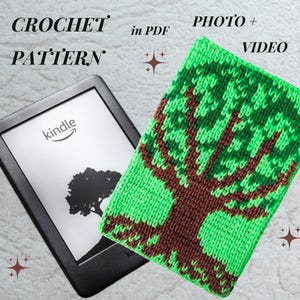 May include: A Kindle e-reader next to a green and brown crocheted tree pattern case. The Kindle displays a tree graphic. The words "CROCHET PATTERN" are at the top left. The words "PHOTO + VIDEO" are at the top right.