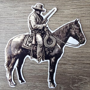 May include: A black and white illustration of a cowboy riding a horse. The cowboy is wearing a hat and holding a rifle. The horse is standing on its hind legs.