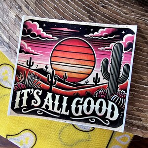 May include: A retro-style illustration of a desert sunset with the text "IT'S ALL GOOD" in a bold, vintage font. The image features a large orange sun with stripes, cacti, and a dark blue sky with pink clouds.