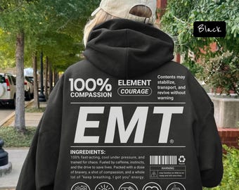 May include: Black hoodie with the word "EMT" in large white letters. The back of the hoodie features text that reads "100% Compassion, Element Courage" and "Ingredients: 100% fast-acting, cool under pressure..." with various icons.