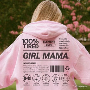 May include: A light pink hoodie with the words "100% Tired" and "Girl Mama" printed on the back. The hoodie also features a list of "ingredients" and icons representing various aspects of motherhood.