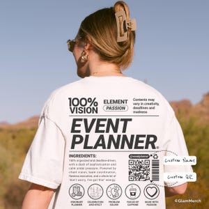 以下が含まれることがあります： 大きな黒い文字で「EVENT PLANNER」と書かれた白いTシャツ。シャツには「100% VISION, ELEMENT PASSION」というテキストと材料のリストも表示されています。QRコードとカスタム名とQRコード用のスペースも表示されています。