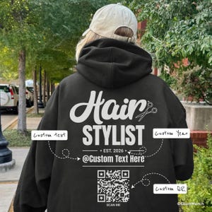 May include: Black hoodie with white text reading "Hair Stylist" and a scissors graphic. Includes "+ EST. 2026 +" and "@Custom Text Here". Features a QR code that says "SCAN ME".