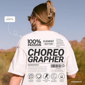 May include: White t-shirt with the text "CHOREOGRAPHER" in large black letters. The shirt also features the words "100% PASSION" and "ELEMENT RHYTHM". Additional text includes "INGREDIENTS" and a list of dance-related elements.