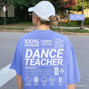 Può includere: Una maglietta blu Flo con le parole "DANCE TEACHER" in grandi lettere bianche. La maglietta presenta anche il testo "100% PASSION" e "ELEMENT RHYTHM". Il testo aggiuntivo include "INGREDIENTS" e icone.
