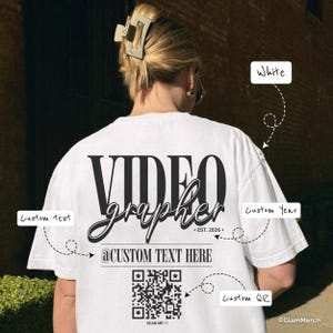 May include: White t-shirt featuring the word "VIDEOGRAPHER" in large black lettering. The shirt also displays the text "@CUSTOM TEXT HERE", a QR code, and "EST. 2026+".