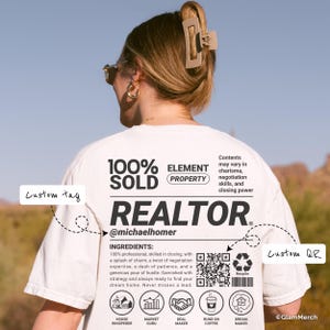 Puede incluir: Camiseta blanca con la palabra "REALTOR" en negrita negra. La camiseta incluye el texto "100% SOLD" y "ELEMENT PROPERTY". Texto adicional describe los ingredientes para el éxito, incluyendo carisma y habilidades de negociación. También hay un código QR e iconos.