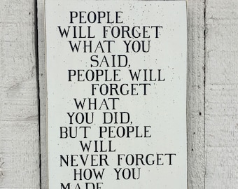 May include: White wooden sign with black text that reads "People will forget what you said, people will forget what you did, but people will never forget how you made them feel - Maya Angelou".
