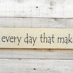 May include: A wooden sign with a white background and black lettering that reads "Do one thing every day that makes you happy".