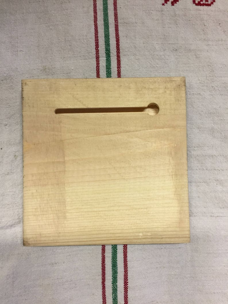 Peut inclure: Une plaque en bois clair et lisse avec une fente rectangulaire et un trou rond dans le coin sup&eacute;rieur droit.