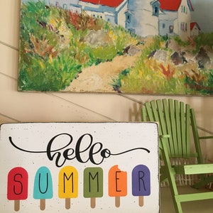 May include: A wooden sign with the text "hello summer" in black cursive script. The word "summer" is spelled out with colorful popsicle graphics.