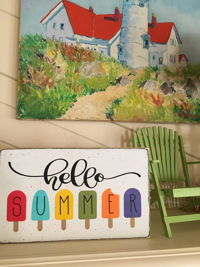 May include: A wooden sign with the text "hello summer" in black cursive script. The word "summer" is spelled out with colorful popsicle graphics.