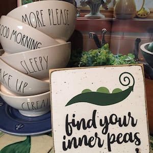 May include: White wooden sign with a green pea pod and the text "find your inner peas".