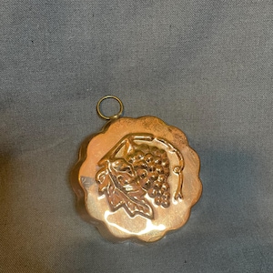 A vintage copper mold for jelly with a grape design.