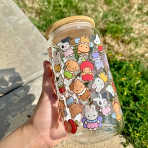 以下が含まれることがあります： カラフルな漫画の動物のステッカーで飾られた、木製の蓋が付いた透明なガラスの瓶。瓶には、クマ、ウサギ、キツネ、鳥など、さまざまな動物のキャラクターが詰められています。