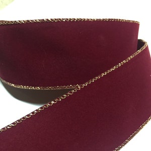 May include: Burgundy velvet ribbon with a gold metallic edge. The ribbon is 2.5 inches wide and has a wired edge.