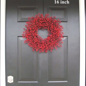 May include: A red berry wreath with a 16 inch diameter, hanging on a black front door.