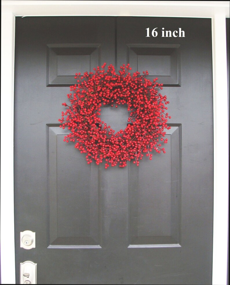 May include: A red berry wreath with a 16 inch diameter, hanging on a black front door.