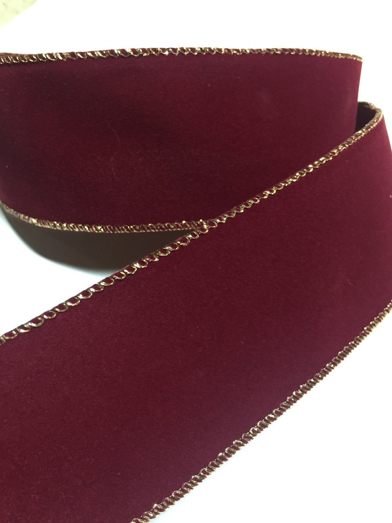 May include: Burgundy velvet ribbon with a gold metallic edge. The ribbon is 2.5 inches wide and has a wired edge.