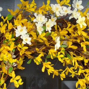 May include: A wreath made of yellow and white flowers. The wreath is made of artificial flowers and is perfect for spring or summer decor.