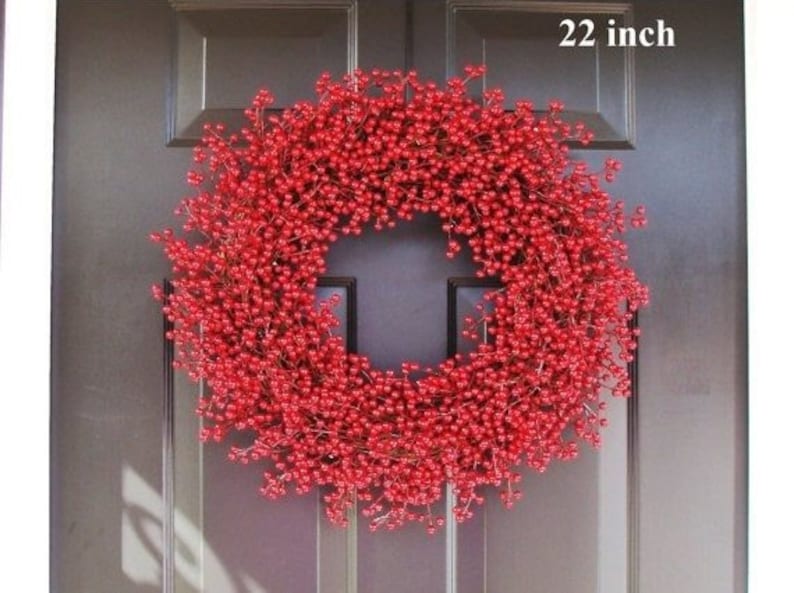 May include: A 22 inch red berry wreath with a dark brown door in the background.