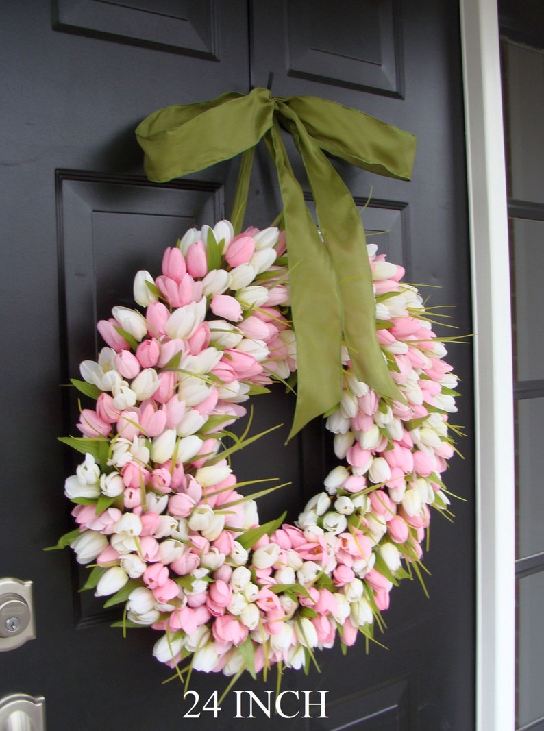 May include: A 24 inch wreath made of pink and white tulips with a green ribbon bow. The wreath is hanging on a black door.