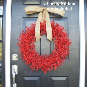 May include: A 24 inch red berry wreath with a burlap bow hanging on a black door. "24 inch, Ribbon not included" is written on the door.