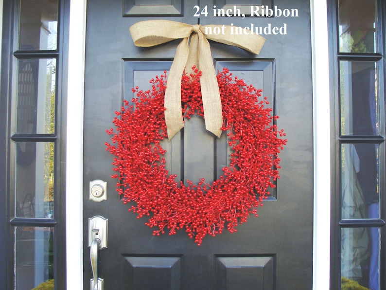 May include: A 24 inch red berry wreath with a burlap bow hanging on a black door. "24 inch, Ribbon not included" is written on the door.