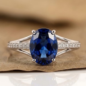 Verlovingsring met 2 karaat blauwe saffier en laboratoriumdiamant, en een trouwring met gespleten band van 14 karaats massief goud voor dames.