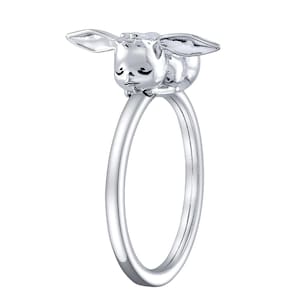 May include: A silver ring with a small, sleeping bunny charm. The bunny is facing to the left and has its eyes closed.