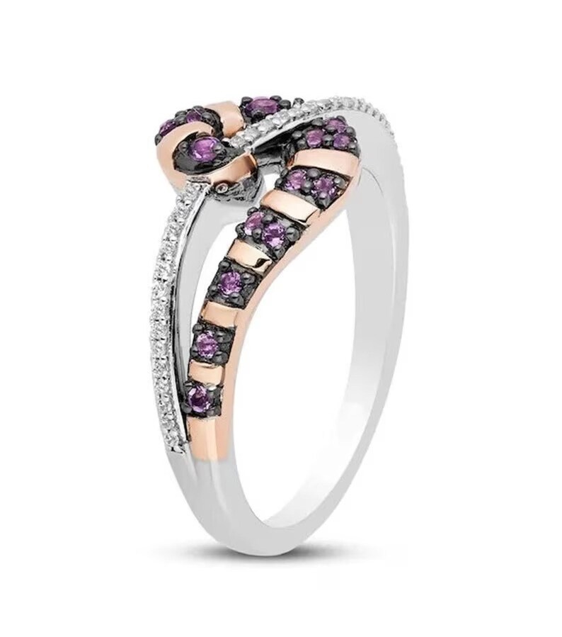 May include: A silver and rose gold ring with a twisted design. The ring is set with small purple and white gemstones.