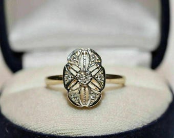 May include: A vintage gold ring with an oval, filigree-style setting. The setting is adorned with small diamonds and a central diamond. The ring is presented in a blue and white jewelry box.