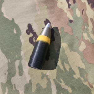 May include: A black and yellow military projectile with a silver tip.