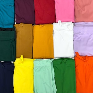 Könnte beinhalten: Eine Sammlung von 18 Stoffmustern in verschiedenen Farben, darunter Türkis, Burgunderrot, Rot, Rosa, Pfirsich, Lavendel, Lila, Senfgelb, Gold, Weiß, Grün, Orange, Gelb, Mintgrün, Dunkelgrün, Marineblau, Schwarz und Hellrosa.
