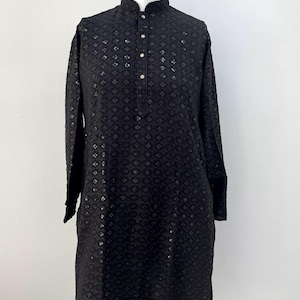 May include: A black long-sleeved shirt with a button-up collar and a geometric pattern. The shirt has a relaxed fit and a slightly longer length.