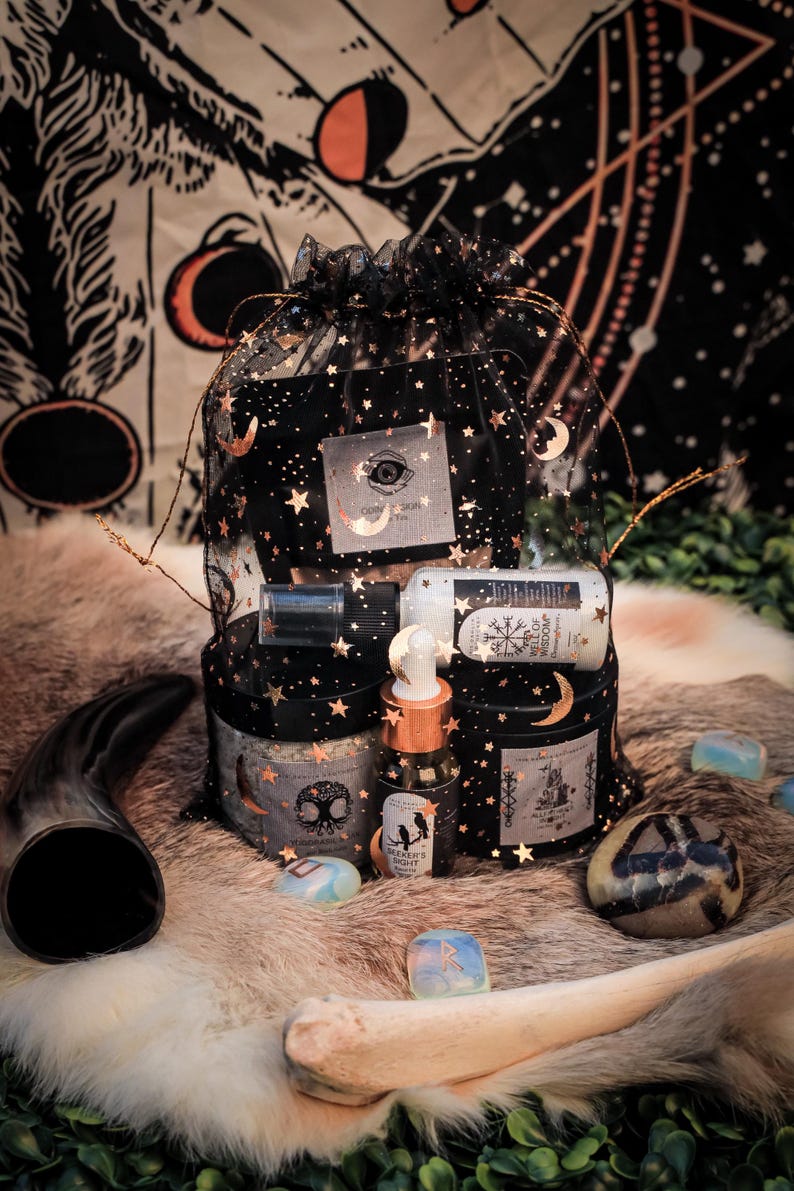 Puede incluir: Una bolsa de malla negra llena de varios art&iacute;culos de boticario, incluyendo frascos, botellas y un peque&ntilde;o vial. La bolsa est&aacute; decorada con estrellas doradas y lunas crecientes. Los art&iacute;culos est&aacute;n dispuestos sobre una superficie similar a la piel.