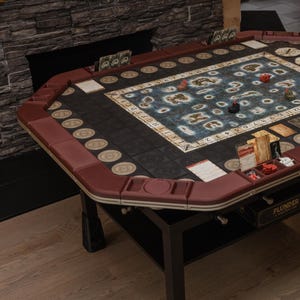 May include: A red and black game table with a game board featuring a map with islands and a compass. The table has a drawer labeled "Plunder: The Treasure Island Game".