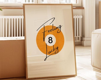May include: A framed print with a white background and a large orange circle with the number "8" in the center. The text "Feeling Lucky" is written in black cursive above the circle.