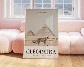 May include: Framed art print featuring a cheetah walking in front of the pyramids. The print has the words "CLEOPATRA PYRAMID COLLECTION" and "SINCE MMXXV" in a serif font. The color palette is neutral with beige, brown, and black.
