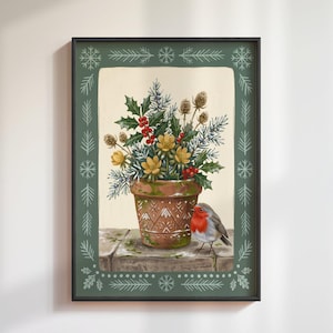 May include: A framed wall art print featuring a terracotta pot filled with holly, red berries, and yellow flowers. A small robin with a red breast stands next to the pot on a stone surface. The border is dark green with white snowflake and pine patterns.