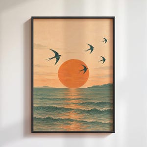 Pode incluir: Uma impressão de arte emoldurada retratando um pôr do sol sobre o oceano com um grande sol laranja centrado acima do horizonte. Quatro pássaros escuros voam no céu contra um fundo pêssego pálido. O mar apresenta ondas azuis com reflexos.
