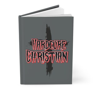 May include: A gray journal with the words "HARDCORE CHRISTIAN" in red and white lettering, with a black cross graphic. The journal is open, revealing white pages.